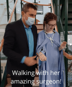 A surgeon helping a girl walk in the hospital after surgery