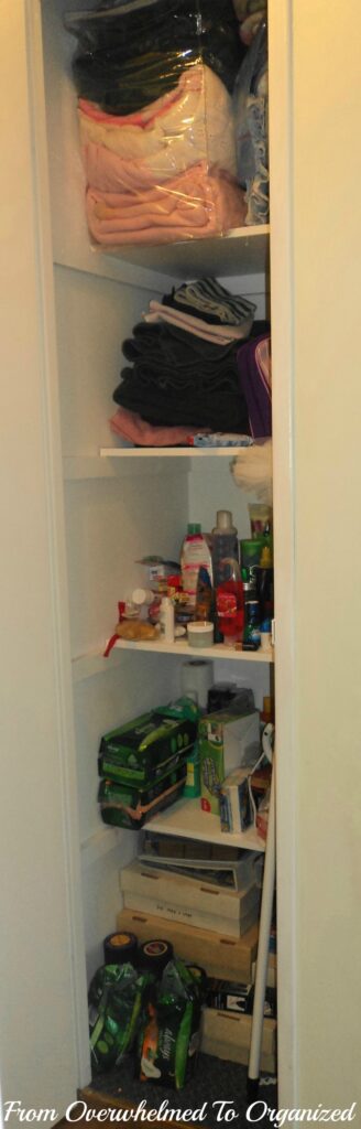Linen closet before organization with bag of blankets stuffed on shelf, towels and toiletries. 