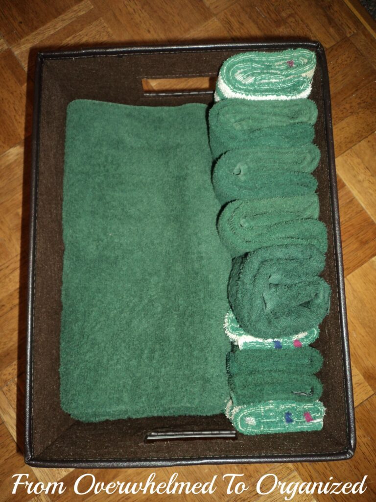 Linen closet after organization. Towels organized in a basket. 