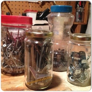 Hardware (nails, bolts, hinges) stored in recycled jars. 