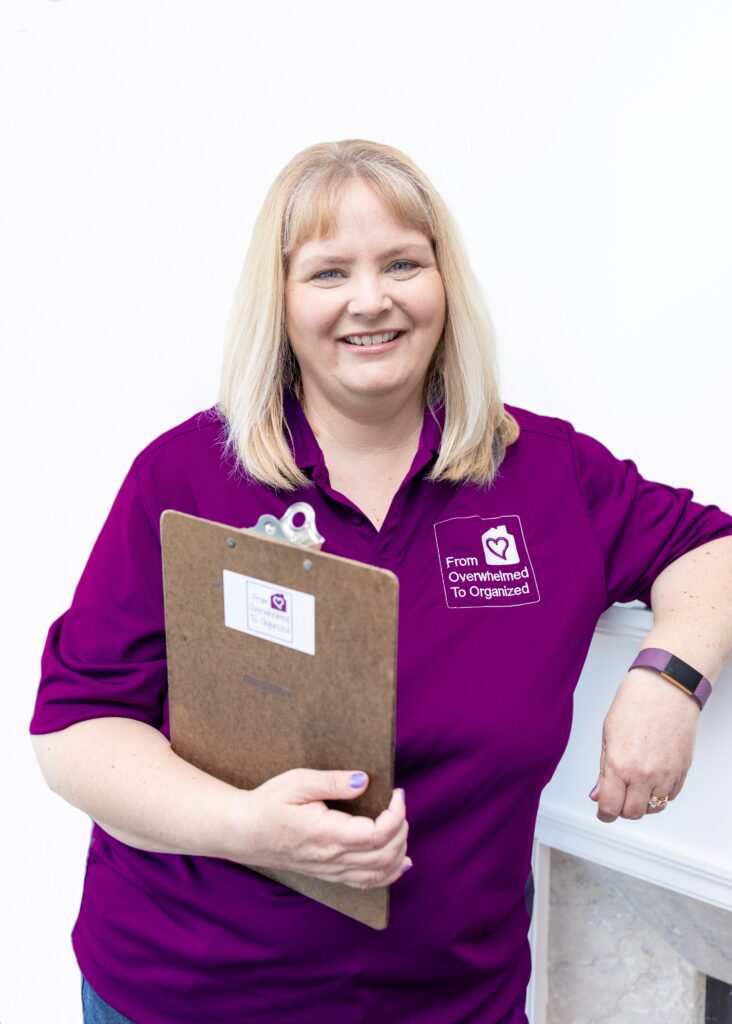 Logo shirt in brand colour Hilda Rodgers is dressed in purple branded gear holding a clipboard ready to help you organize your home.