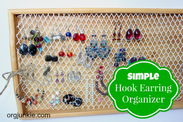 Orgjunkie.com. Simple hook earring organizer. Earring organizer from a wire waste basket and a tray. Several beaded hook earrings hang from wire mesh that had been attached to light stained wooden tray.