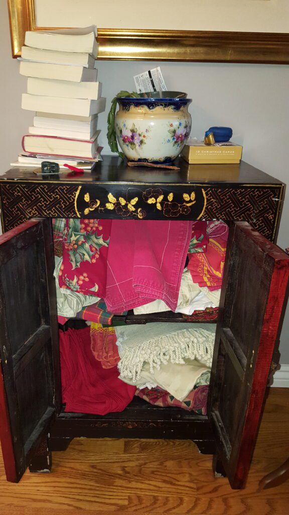 Cluttered linen cabinet before organization.