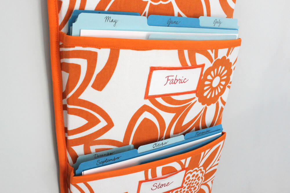 Hanging pocket organizer. Orange and white floral fabric with solid orange trim. 