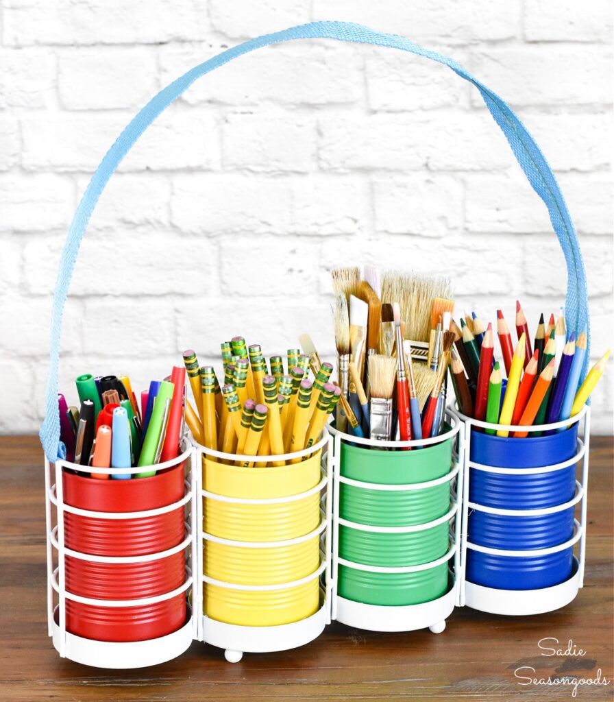 Sadie Seasongoods. Cans painted primary colours set inside a utensil holder to store pencils, pens and paint brushes. 
