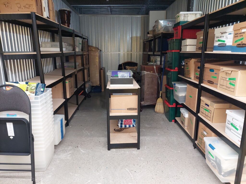 Interior of storage unit lined with shelves with banker boxes. 